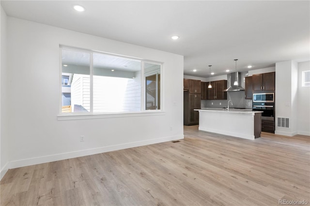 5271 Rendezvous Pkwy, Timnath, CO 80547 - kitchen with wall chimney range hood, stainless steel microwave, decorative backsplash, recessed lighting, and baseboards