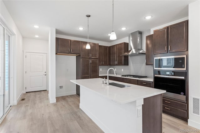 5271 Rendezvous Pkwy, Timnath, CO 80547 - kitchen with appliances with stainless steel finishes, wall chimney range hood, a sink, light wood-style flooring, and recessed lighting