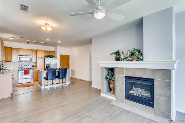 13456 Via Varra Unit 315, Broomfield, CO 80020 - living room with a tiled fireplace, light wood-style flooring, baseboards, and a ceiling fan