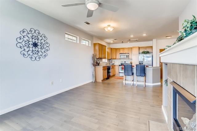 13456 Via Varra Unit 315, Broomfield, CO 80020 - kitchen with appliances with stainless steel finishes, a ceiling fan, a breakfast bar, light wood finished floors, and light countertops