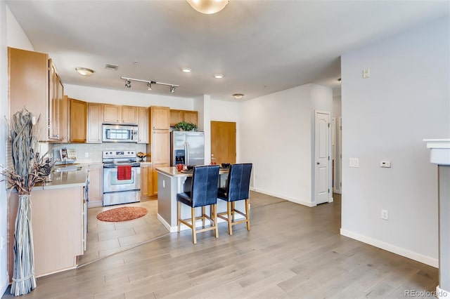 13456 Via Varra Unit 315, Broomfield, CO 80020 - kitchen featuring stainless steel appliances, a center island, a kitchen bar, backsplash, and light countertops