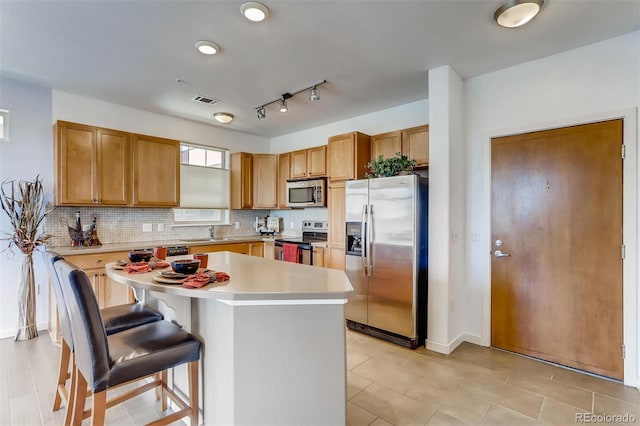 13456 Via Varra Unit 315, Broomfield, CO 80020 - kitchen with stainless steel appliances, decorative backsplash, a kitchen breakfast bar, a kitchen island, and a sink