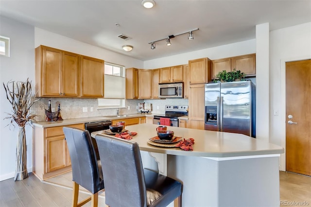13456 Via Varra Unit 315, Broomfield, CO 80020 - kitchen with stainless steel appliances, a sink, light countertops, backsplash, and a kitchen island