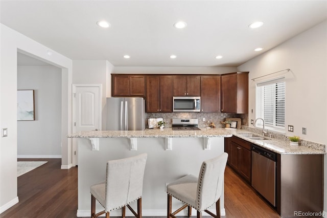 kitchen with decorative backsplash, appliances with stainless steel finishes, a kitchen island, and sink