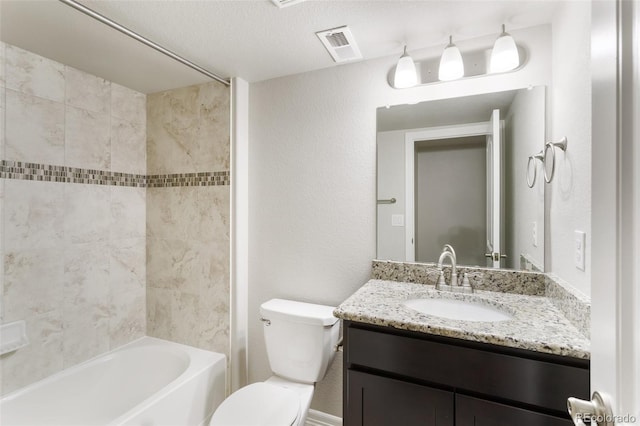 full bathroom with a textured ceiling, vanity, tiled shower / bath combo, and toilet