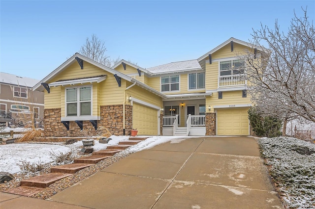 craftsman-style home with stone siding, driveway, a porch, and an attached garage