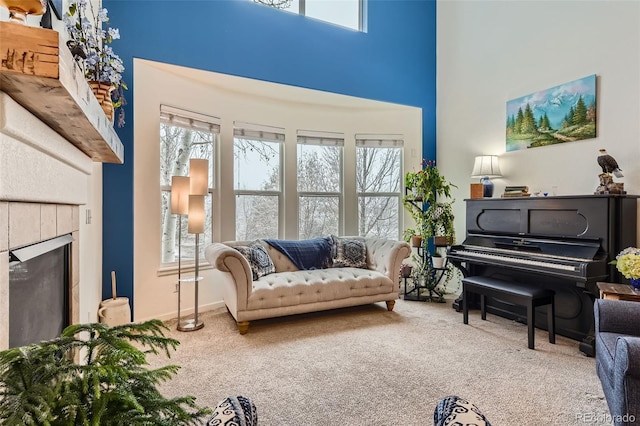 sitting room featuring carpet floors, a towering ceiling, plenty of natural light, and a fireplace