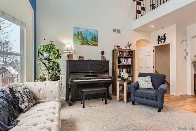 living area featuring arched walkways, carpet flooring, baseboards, and a towering ceiling