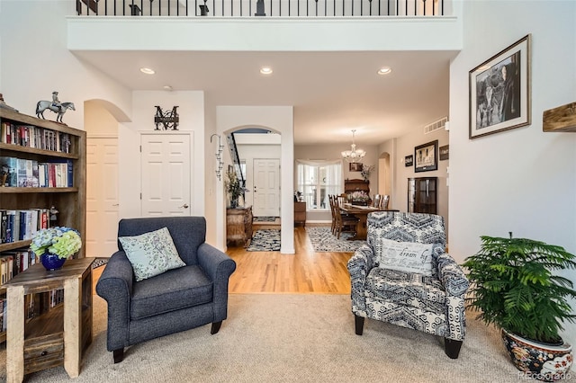 living room featuring arched walkways, a chandelier, recessed lighting, wood finished floors, and carpet