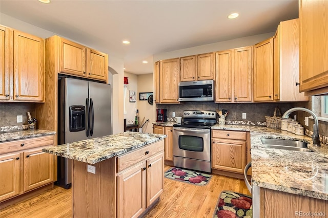 kitchen featuring appliances with stainless steel finishes, a sink, tasteful backsplash, recessed lighting, and light stone countertops