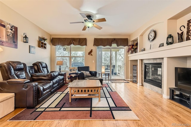 living area with wood finished floors, a ceiling fan, and a fireplace