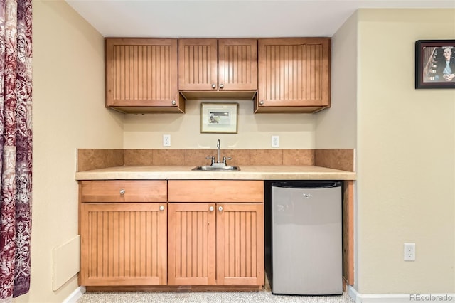kitchen featuring fridge, a sink, light countertops, and baseboards