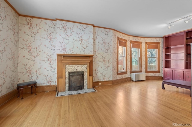 unfurnished living room with hardwood / wood-style flooring, crown molding, and radiator