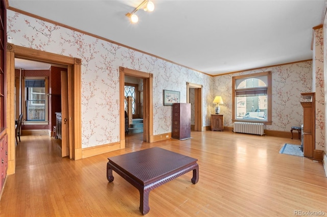 living room featuring crown molding, radiator heating unit, and light wood-type flooring