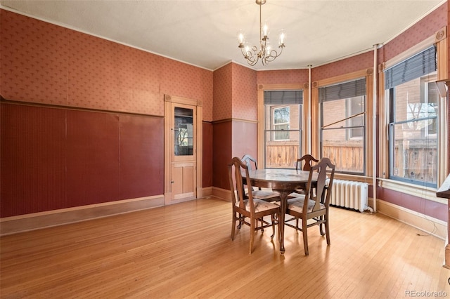 dining room featuring crown molding, a notable chandelier, radiator heating unit, and light wood-type flooring