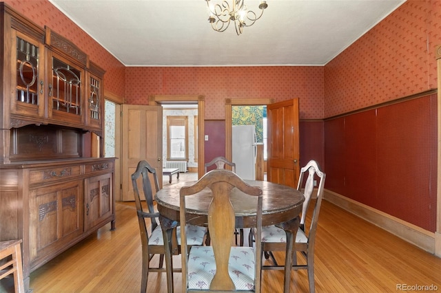 dining area featuring a notable chandelier, radiator heating unit, and light wood-type flooring