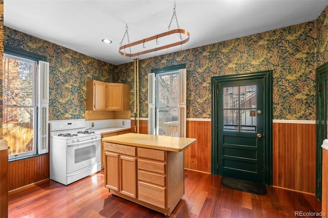 kitchen featuring hardwood / wood-style flooring, a center island, light brown cabinetry, and gas range gas stove