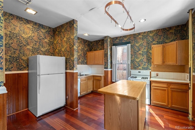 kitchen with sink, white appliances, dark hardwood / wood-style floors, and a center island