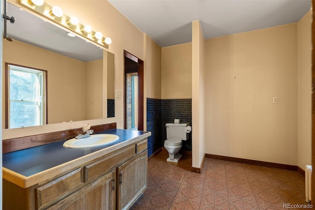 bathroom with tile walls, vanity, tile patterned flooring, and toilet