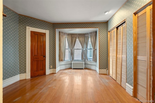 unfurnished bedroom with radiator, two closets, and light hardwood / wood-style floors