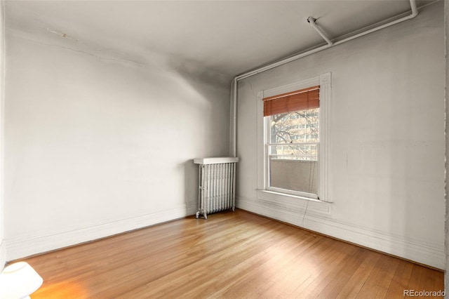 unfurnished room featuring hardwood / wood-style flooring and radiator heating unit