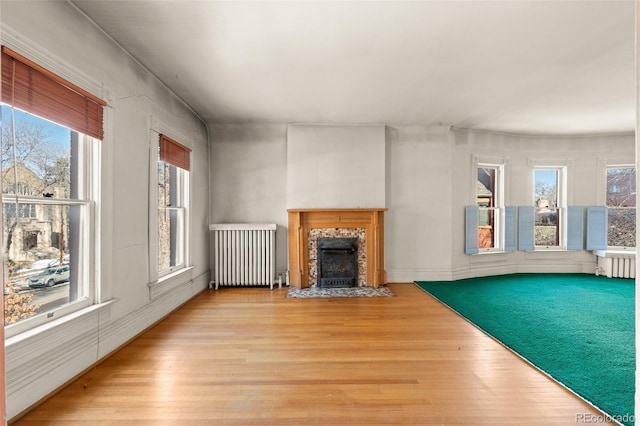 unfurnished living room featuring radiator heating unit, a high end fireplace, and light hardwood / wood-style flooring