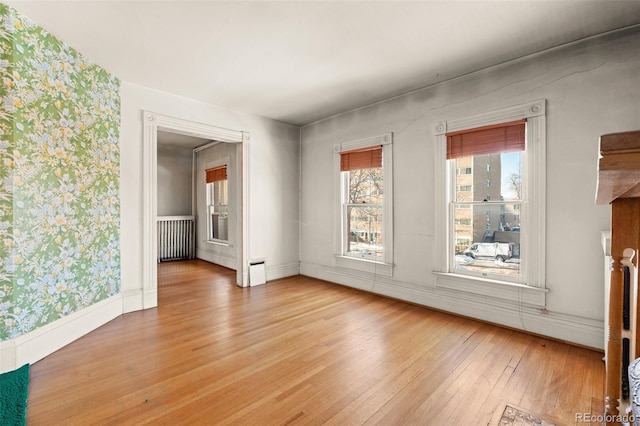 empty room with radiator heating unit and light hardwood / wood-style flooring