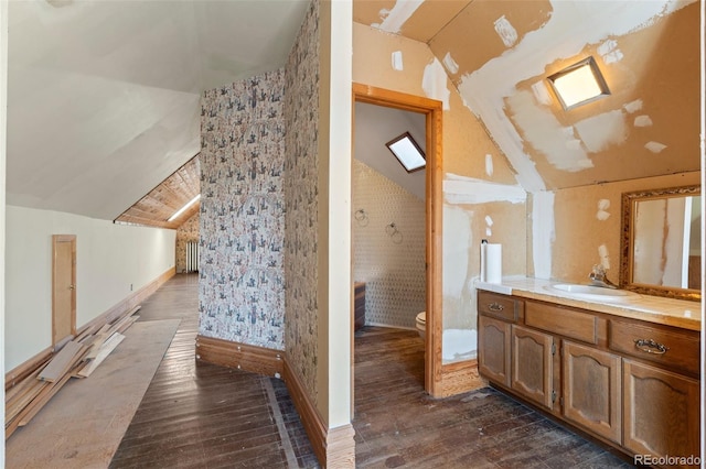 bathroom with lofted ceiling, toilet, and wood-type flooring