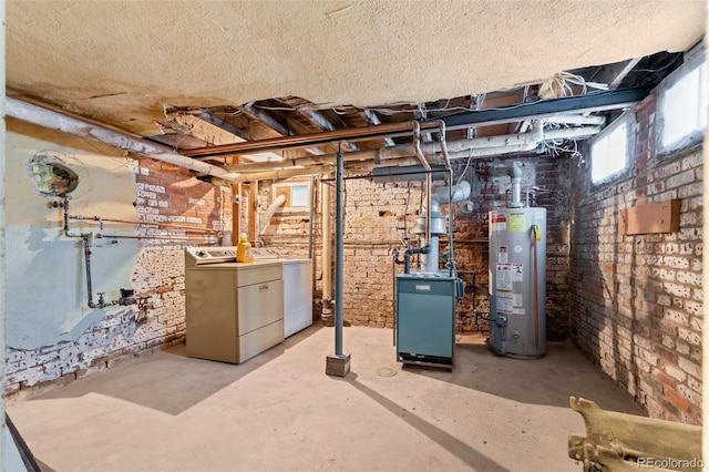 basement with washer and dryer, water heater, a textured ceiling, and brick wall