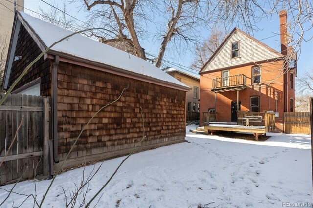 snow covered rear of property featuring a balcony