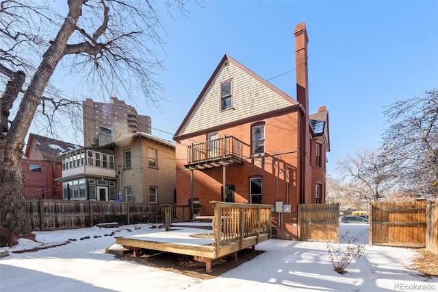 snow covered back of property featuring a wooden deck