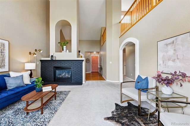 3240 W 114th Cir Unit D, Westminster, CO 80031 - carpeted living area featuring a towering ceiling, arched walkways, a fireplace, and baseboards
