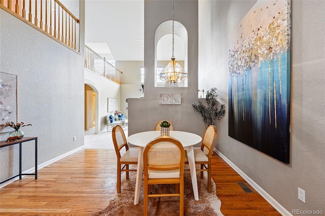 3240 W 114th Cir Unit D, Westminster, CO 80031 - dining area with arched walkways, a chandelier, a towering ceiling, wood finished floors, and a textured wall
