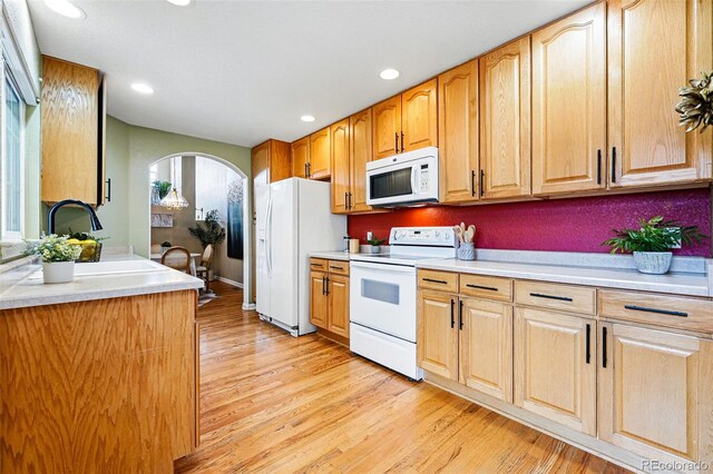 3240 W 114th Cir Unit D, Westminster, CO 80031 - kitchen featuring white appliances, arched walkways, a sink, light wood finished floors, and light countertops