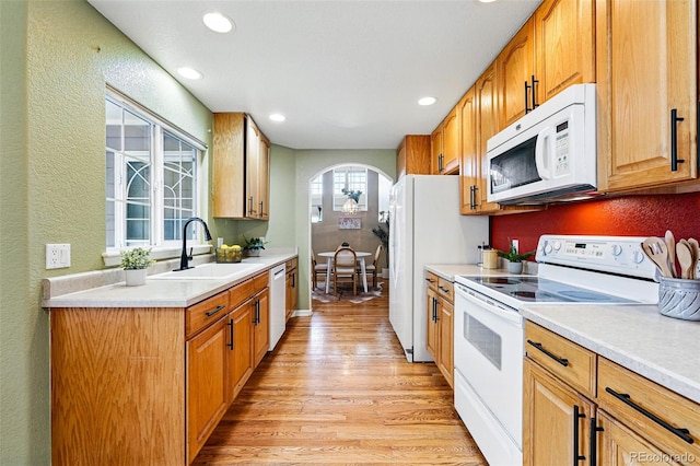 3240 W 114th Cir Unit D, Westminster, CO 80031 - kitchen featuring white appliances, a sink, arched walkways, light wood-type flooring, and a textured wall