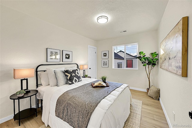 bedroom featuring a textured ceiling and light hardwood / wood-style flooring