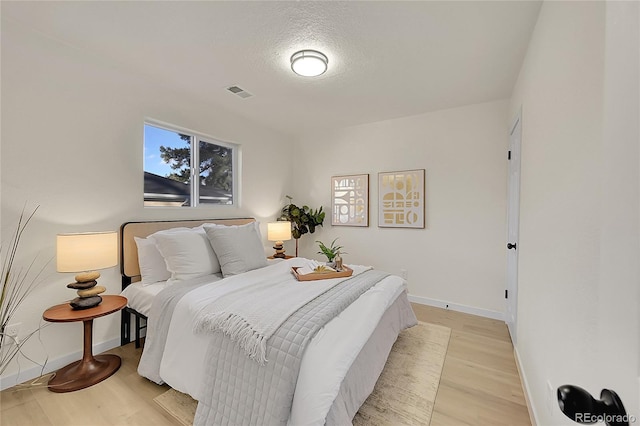 bedroom featuring a textured ceiling and light hardwood / wood-style flooring