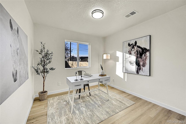 office featuring light wood-type flooring and a textured ceiling