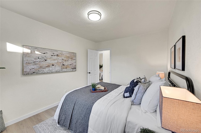 bedroom featuring a textured ceiling and light hardwood / wood-style flooring