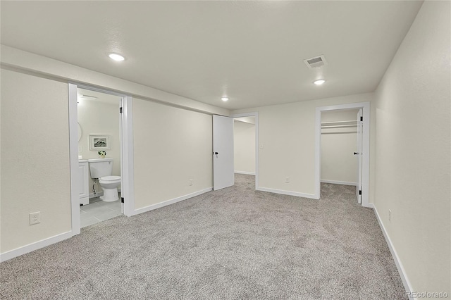 unfurnished bedroom featuring ensuite bathroom, light carpet, and a closet