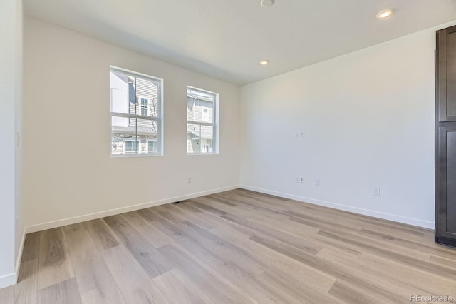 spare room with recessed lighting, baseboards, and light wood-type flooring