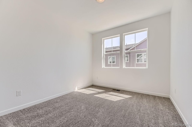 unfurnished room featuring carpet and baseboards