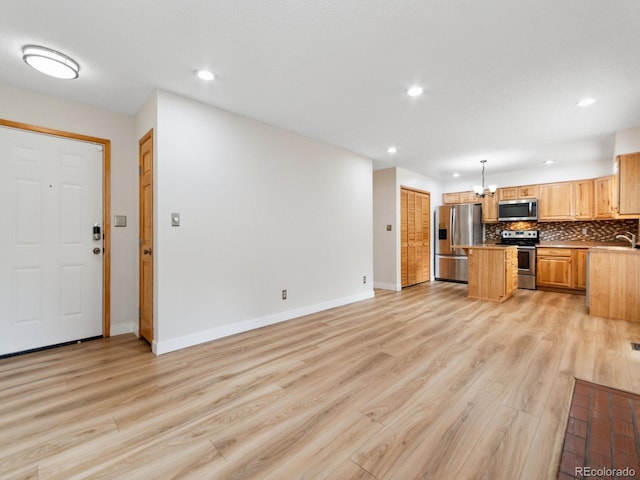 interior space with appliances with stainless steel finishes, light hardwood / wood-style floors, and tasteful backsplash