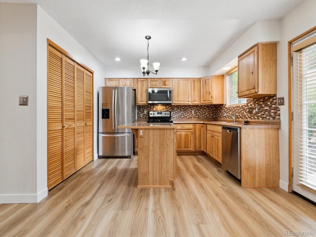 kitchen featuring a center island, light hardwood / wood-style flooring, backsplash, and stainless steel appliances