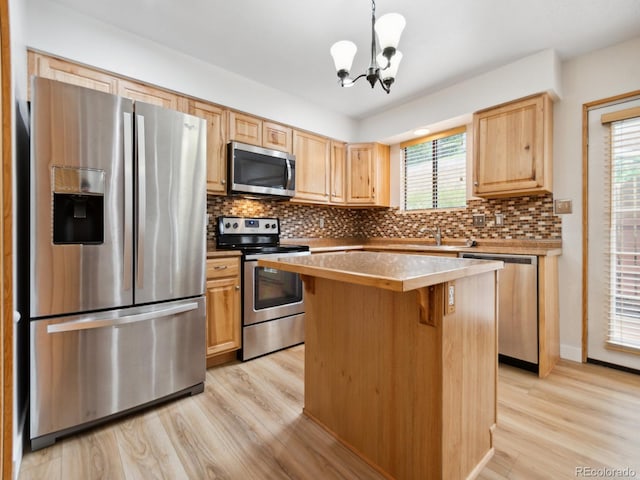 kitchen featuring appliances with stainless steel finishes, light hardwood / wood-style floors, decorative backsplash, a wealth of natural light, and a kitchen island