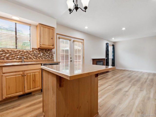 kitchen with decorative backsplash, sink, light wood-type flooring, a breakfast bar area, and a center island