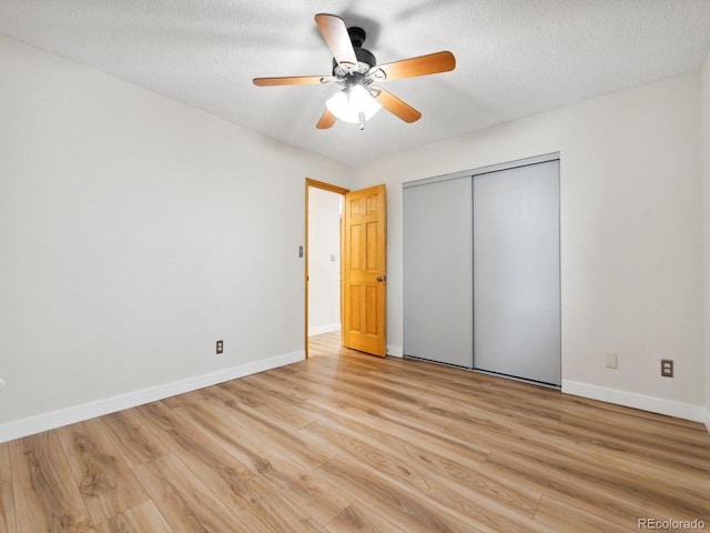 unfurnished bedroom with a textured ceiling, a closet, ceiling fan, and light wood-type flooring