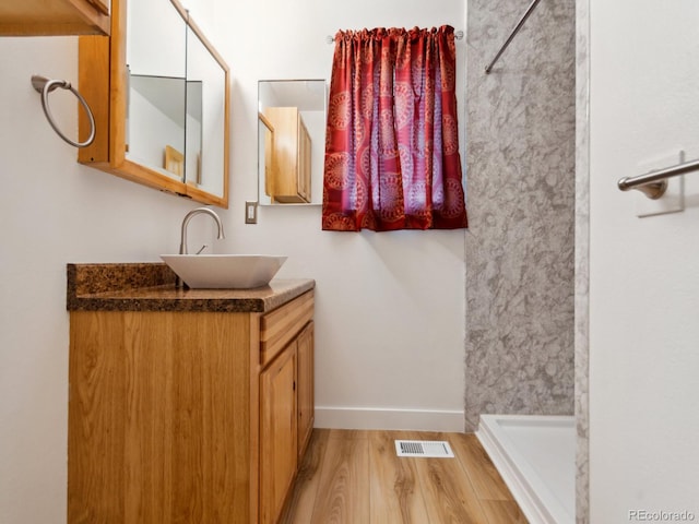 bathroom with hardwood / wood-style floors, a shower, and vanity