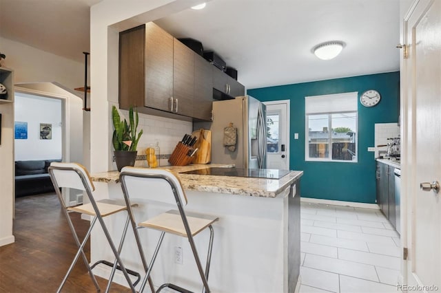 2870 Pontiac St, Denver, CO 80207 - kitchen featuring stainless steel fridge, a breakfast bar area, backsplash, a peninsula, and black electric stovetop