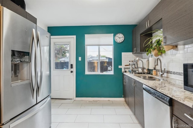 2870 Pontiac St, Denver, CO 80207 - kitchen featuring appliances with stainless steel finishes, a sink, light tile patterned floors, tasteful backsplash, and dark brown cabinetry